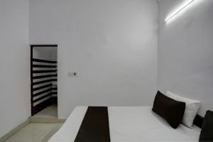 阿里格尔OYO HOTEL KAVYA RESIDENCY的白色客房,配有黑色枕头的床