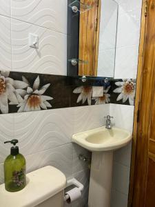 麦德林Pacifica Hostel的浴室设有水槽,墙上挂有鲜花的卫生间