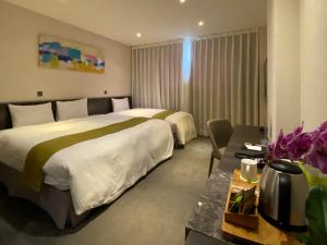 花莲市成旅晶赞饭店-花莲假期的酒店客房设有两张床和一张桌子。