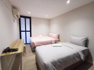 吉隆坡Autumn Guesthouse's near Jalan Alor Bukit Bintang的客房设有两张床、一张桌子和一张书桌。