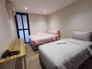 吉隆坡Autumn Guesthouse's near Jalan Alor Bukit Bintang的客房设有两张床、一张桌子和一张书桌