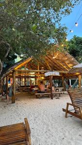 RincónHostel Beach House的沙滩上的木亭子,长有长椅和树木