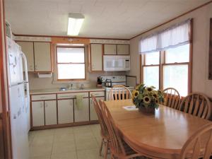 希普博特姆Ship Bottomocean Front First Floor Duplex的厨房配有木桌、椅子和冰箱
