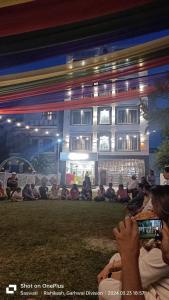 瑞诗凯诗Lifespace Rishikesh- Hotel, Hostel, Cowork, Cafe的一群人坐在一座建筑前面的草上