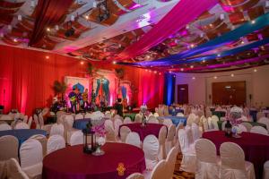 民都鲁民都鲁园市艾佛利酒店的宴会厅配有白色的桌椅和紫色的窗帘