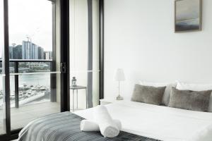 墨尔本Pars Apartments - Collins Wharf Waterfront, Docklands的卧室设有白色的床和大窗户
