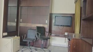 斋浦尔raminder singh ghai的一间房间,配有两把椅子和一台电视