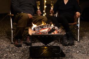白马村Hakuba Jade Chalet by Jade Group的两个人坐在火炉边,喝杯酒