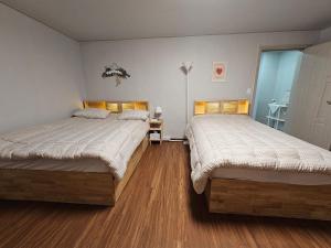 江陵市Happy Jumunjin House的铺有木地板的客房内的两张床