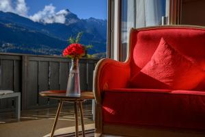加尔米施-帕滕基兴加米斯切霍夫环保酒店 的一张红色的椅子和一张桌子上的花瓶