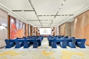 深圳Kare Hotel,Qianhai,Shenzhen的一间会议室,配有蓝色椅子和投影屏幕