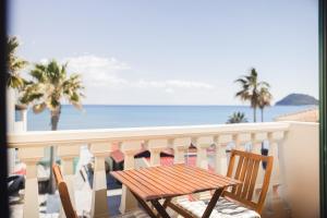 拉加纳斯Manthos Beachfront Apartments的阳台上的木桌和椅子