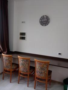 坎特洛Hotel motel residence Gonzaga的一张桌子,上面有四把椅子和墙上的时钟