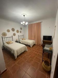 塞维利亚Casa con piscina privada的客房设有两张床、一张桌子和电视。