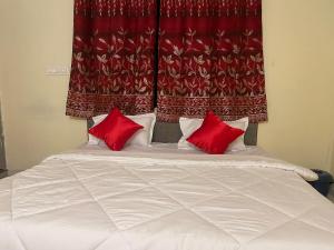 那格浦尔Hotel Kings Inn的窗帘前的一张带两个红色枕头的床