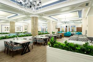 奇姆肯特Shymkent Grand Hotel的一间带桌椅和吊灯的餐厅