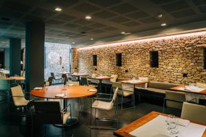 阿尔塔夫拉Hotel Gran Claustre Restaurant & Spa的一间带桌椅和石墙的餐厅