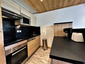 里蒙纽耶Résidence Courmayeur - 2 Pièces pour 4 Personnes 934的厨房配有黑色台面和木制橱柜