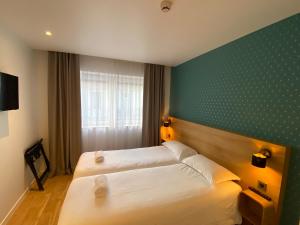 安纳马斯Oskar Hotel的酒店客房设有两张床和绿色的墙壁。