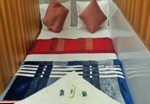 孟买HOTEL AMAAN PALACE的一张带红色白色和蓝色毯子和枕头的床
