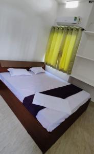 菩提伽耶Glamour Palace的一间卧室配有一张带黄色窗帘的大床