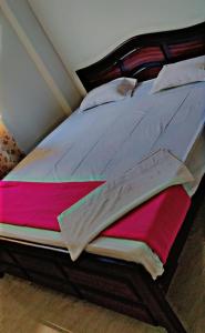 菩提伽耶Glamour Palace的一间卧室配有一张大床,配有粉红色和灰色床单