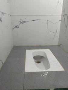 孟买HOTEL AMAAN PALACE的浴室内有白色的厕所,墙壁被裂缝隔开