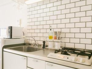 那霸Aiwa Mansion / Vacation STAY 80384的厨房设有水槽和白色瓷砖墙。