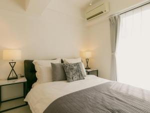 那霸Aiwa Mansion / Vacation STAY 80384的一间卧室配有一张床、两盏灯和一个窗户。