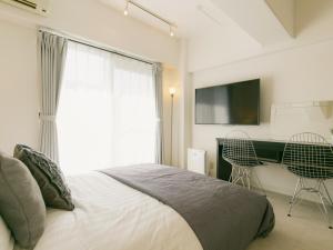 那霸Aiwa Mansion / Vacation STAY 80384的一间卧室配有一张床、一张书桌和一台电视