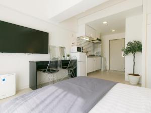 那霸Aiwa Mansion / Vacation STAY 80384的一间带一张床和一张书桌的卧室和一间厨房