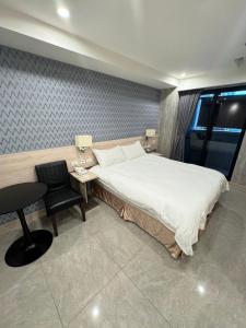 台北珂曼旅馆的一间卧室配有一张床、一张桌子和一把椅子