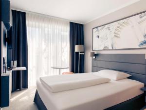 慕尼黑慕尼黑斯彻瓦宾美居酒店的卧室设有白色的床和大窗户