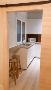 毕尔巴鄂BilboAppartment的厨房配有白色橱柜、水槽和凳子