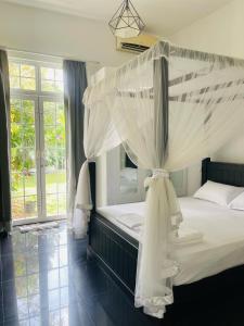MahabageRoshe-Sky Guest House Colombo的卧室配有带白色蚊帐的天蓬床。