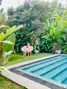 MahabageRoshe-Sky Guest House Colombo的坐在泳池旁的浴缸里的人