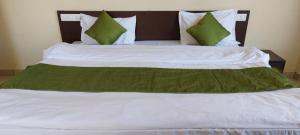 康格拉Mountain Villa Mcleodganj的一张配有绿色和白色床单及枕头的大床