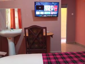 洛德瓦尔Quanam Woods Hotel的卧室设有水槽和墙上的电视。