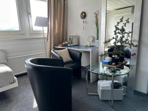 图芬„gg“ games garni Hotel Säntis的客厅配有两把椅子和一张玻璃桌