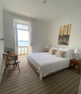 洛帕德Hotel Glavovic的白色的卧室设有一张大床和一个窗户