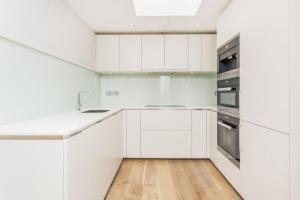 伦敦Boutique Covent Garden Apartment的白色的厨房配有白色橱柜和木地板