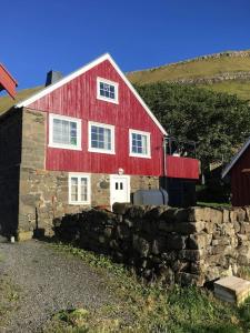 OyndarfjørðurSeaside Cottage的前面有石墙的红色谷仓