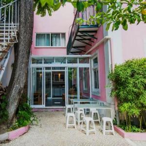 里斯本Safestay Lisbon Bairro Alto的粉红色的建筑,前面设有桌椅