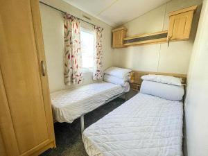 劳斯Superb 6 Berth Caravan At Sunnydale Holiday Park Ref 35079a的小房间设有两张床和窗户