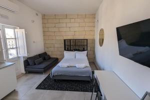 科斯皮夸Casa Cospicua KNight Residency的一间卧室配有一张床和一张沙发