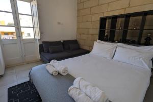 科斯皮夸Casa Cospicua KNight Residency的卧室配有一张白色的大床和一张沙发。
