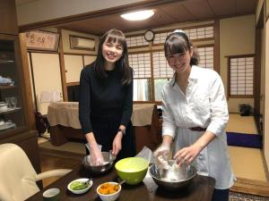 熊本KOTO TEA HOUSE - Vacation STAY 12837的两名妇女站在厨房准备食物