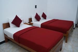亭可马里Hotel Theevanni Inn的客房内的两张床,配有红色和白色床单