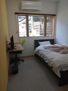 直岛町Naoshima Accommodation Menjuku Ura - Vacation STAY 25585v的一间卧室配有一张床、一张书桌和一个窗户。