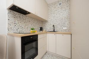 华沙Pereca Stylish Apartment Warsaw & Air Conditioning by Rent like home的厨房配有白色橱柜和黑烤箱。
